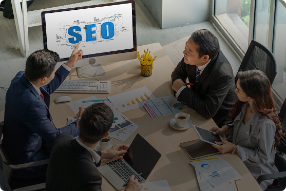 Business meeting with people discussing SEO strategy around a table with a computer screen showing SEO text
